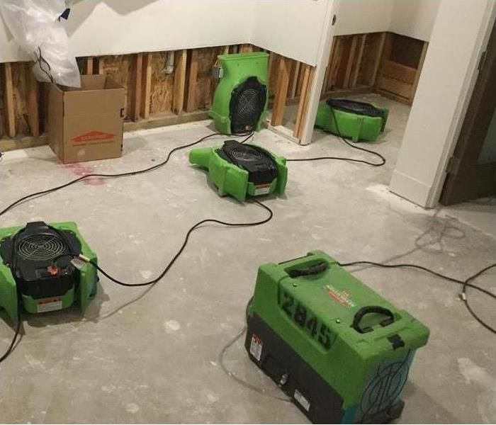 Four air movers placed on the floor and against drywall, flood cuts performed on drywall