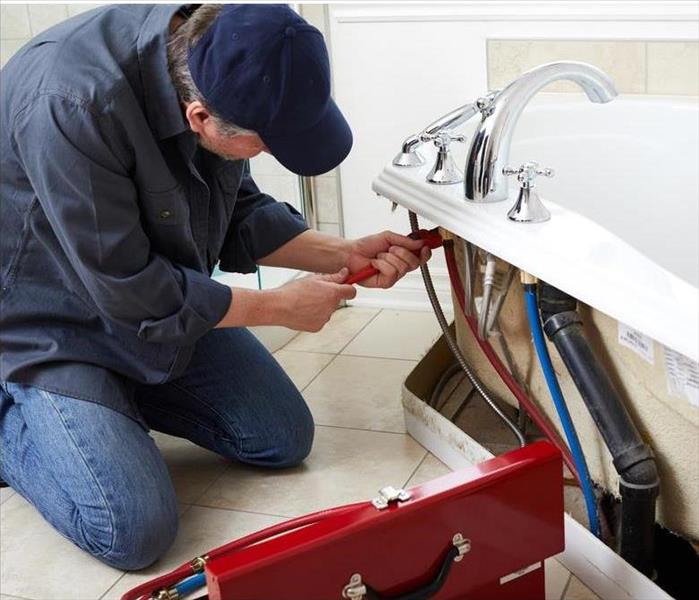 A plumber is fixing a bathtub
